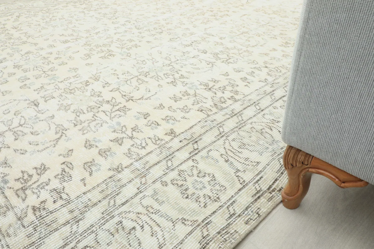 Cream Floral Anatolian Rug in a room, with a furniture leg at the edge, showing scale and placement