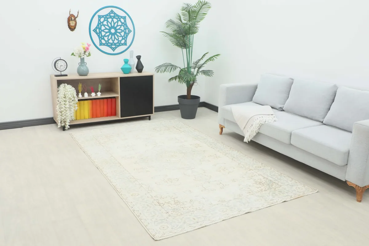 Ivory and blue vintage rug placed under a sofa in a modern living room setting.