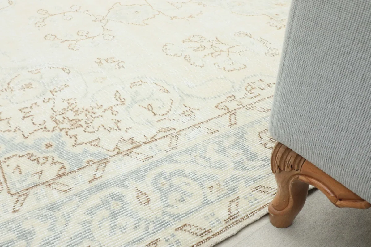 Close-up of the rug's edge next to a furniture leg, illustrating the low pile height.