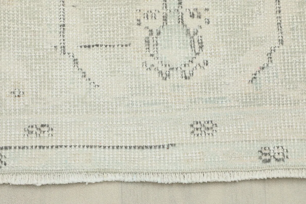 Close-up detail of the rug's low pile and visible hand-knotted texture with subtle gray patterns