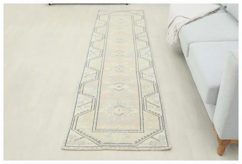 Full top view of the 2'4" x 9'0" vintage Anatolian runner rug with beige, rose, and blue geometric patterns.