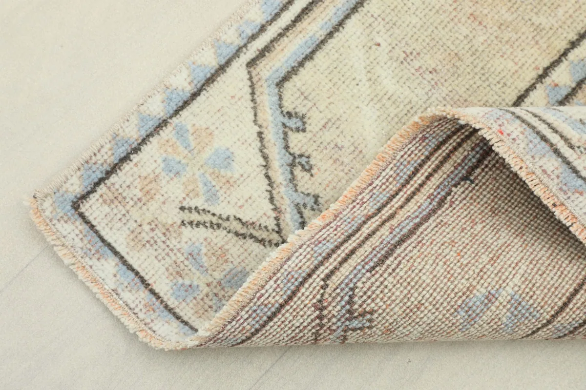View of the rug's edge, showing the low wool pile and the construction of the hand-knotted piece.