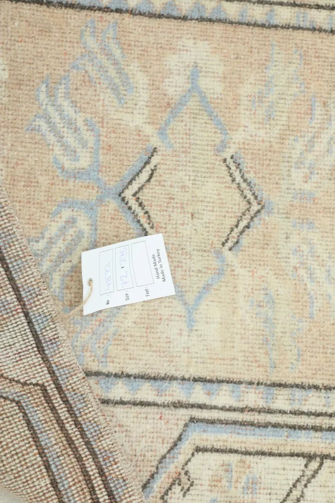Close-up of the rug's back, revealing the hand-knotted cotton foundation and a product tag.