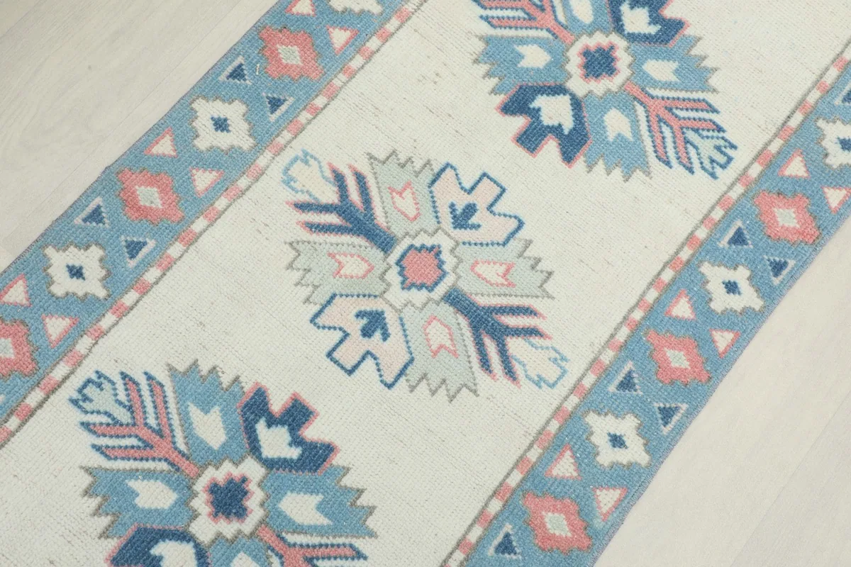 Angled close-up showing several central geometric motifs and the side border of the rug