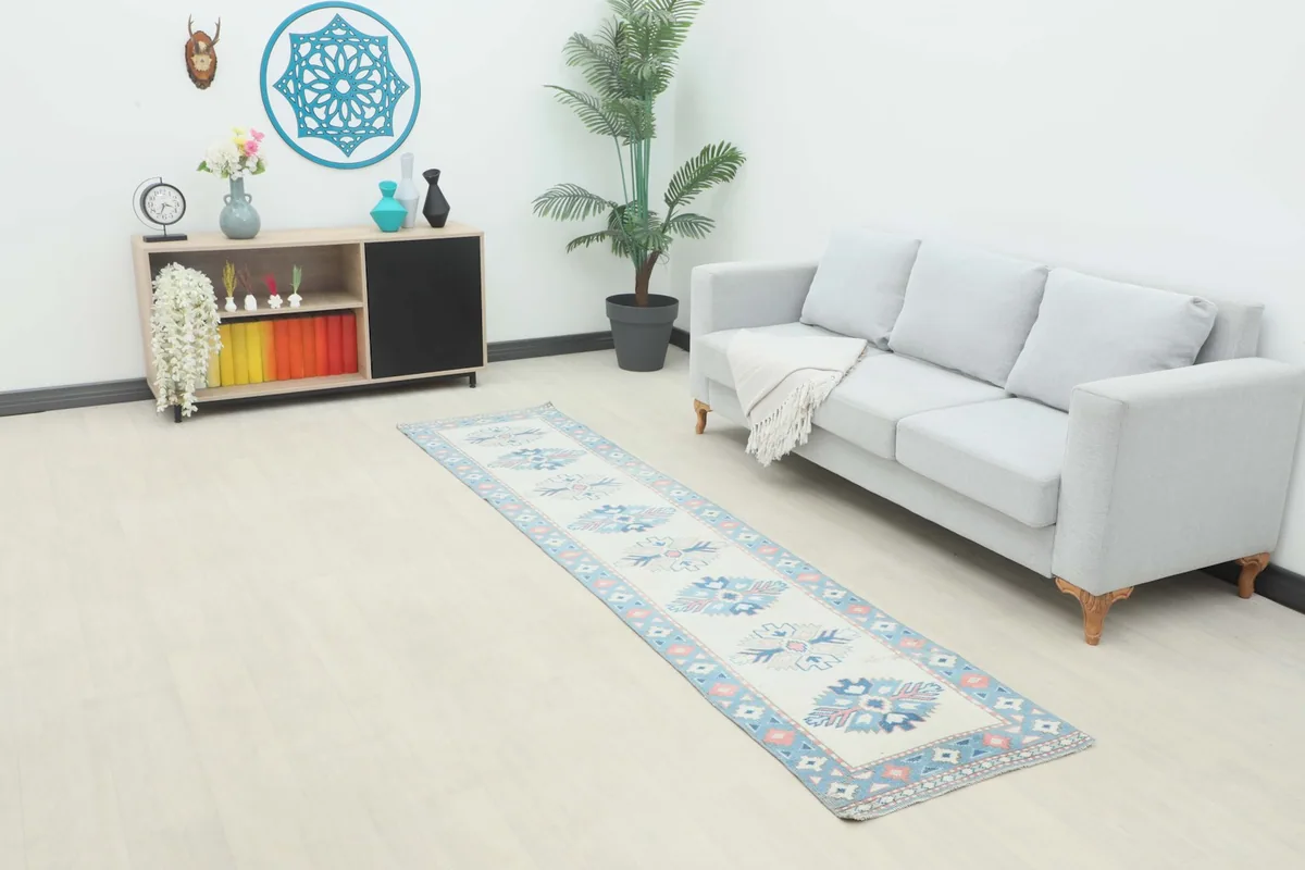 Long view of the vintage runner rug laid out in a modern living space with a light sofa