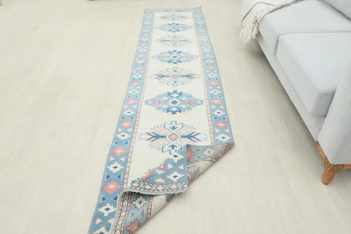 Runner rug partially unrolled in a room, emphasizing its length and decorative appeal