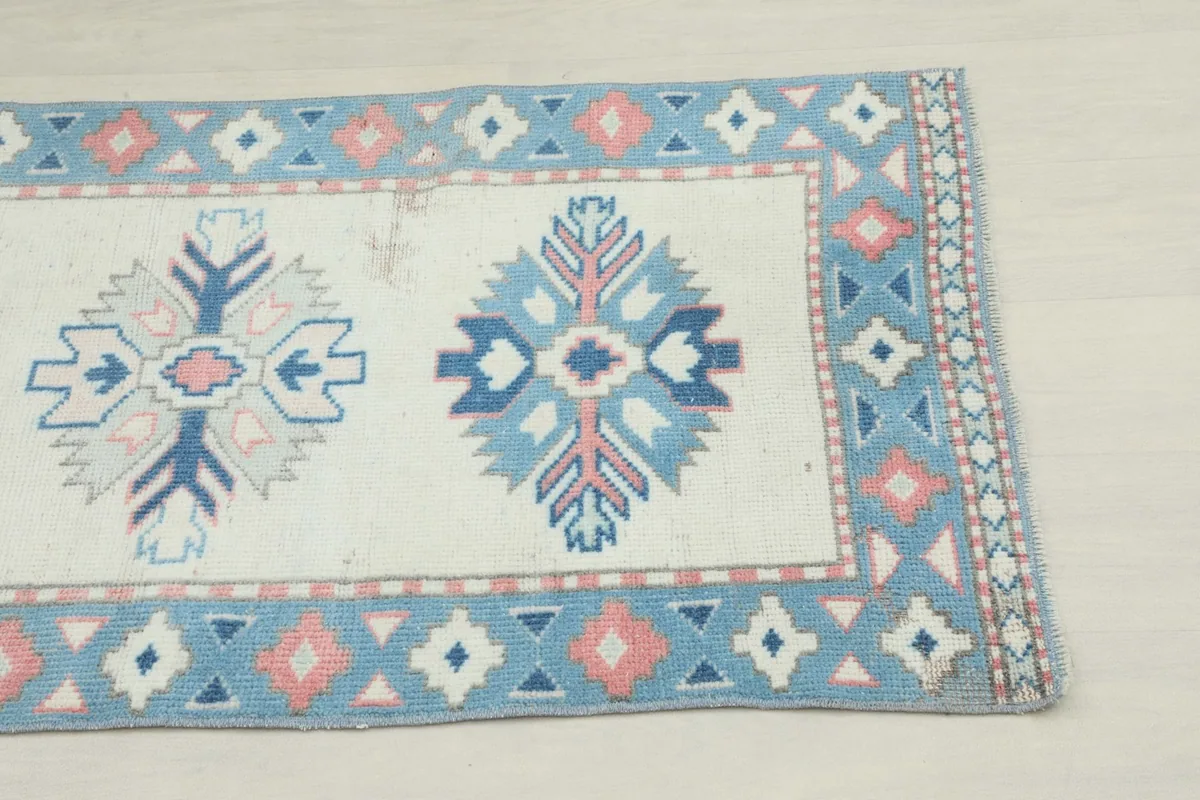 Close-up of one end of the runner rug, highlighting the ivory field and blue and rose border