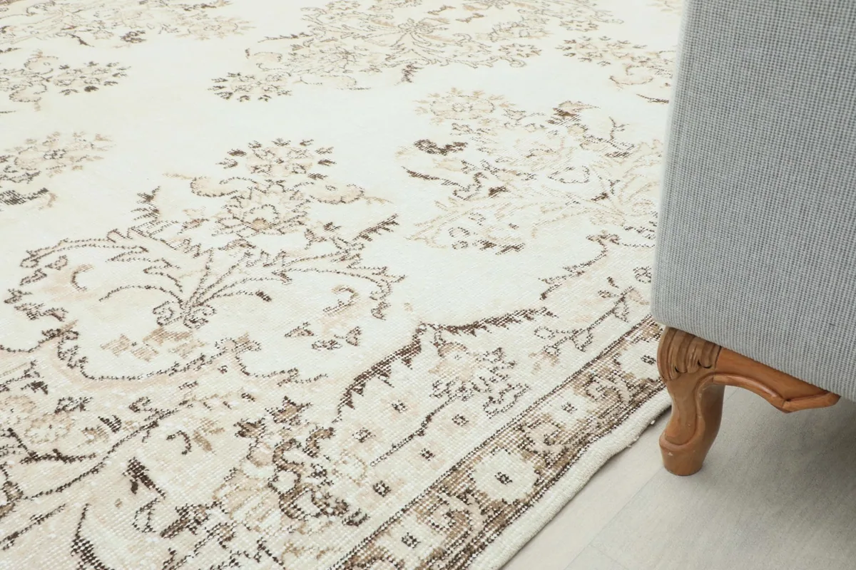 Rug in a room setting, showing the corner next to a sofa leg, emphasizing scale and style