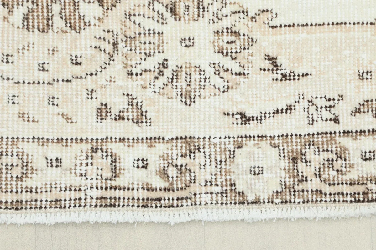 Close-up of the rug's border and fringe, showing the hand-knotted texture and brown patterns