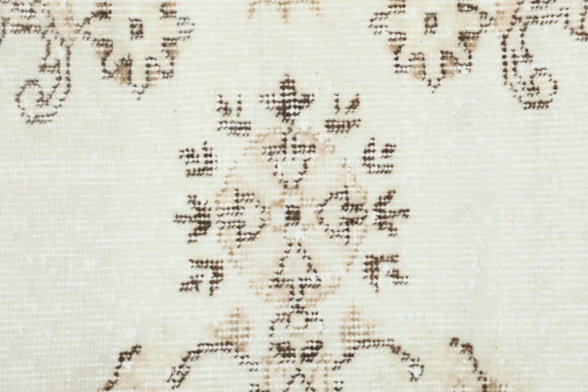 Detailed view of the intricate floral motifs and subtle color variations on the ivory field