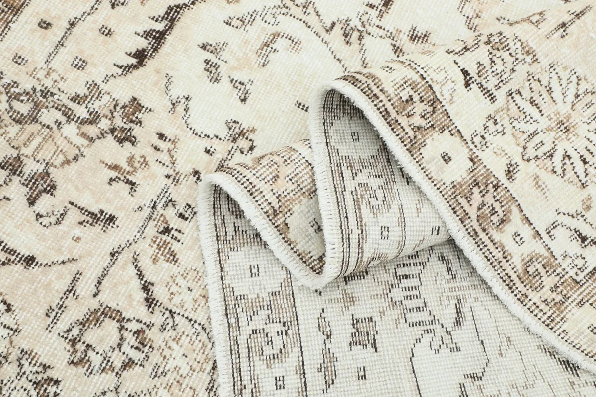 Rug rolled partially to display the texture of the wool pile and the hand-knotted construction