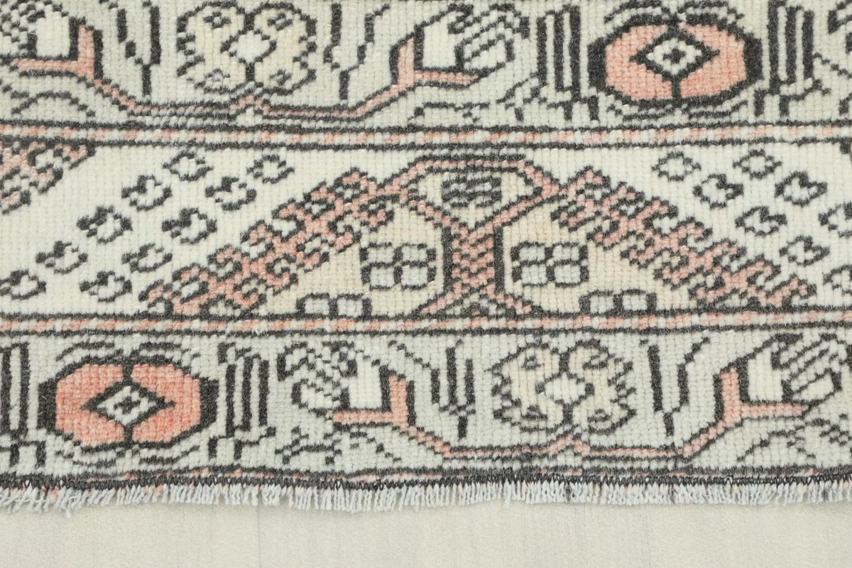 Close-up of the border pattern showing geometric motifs in rose and gray