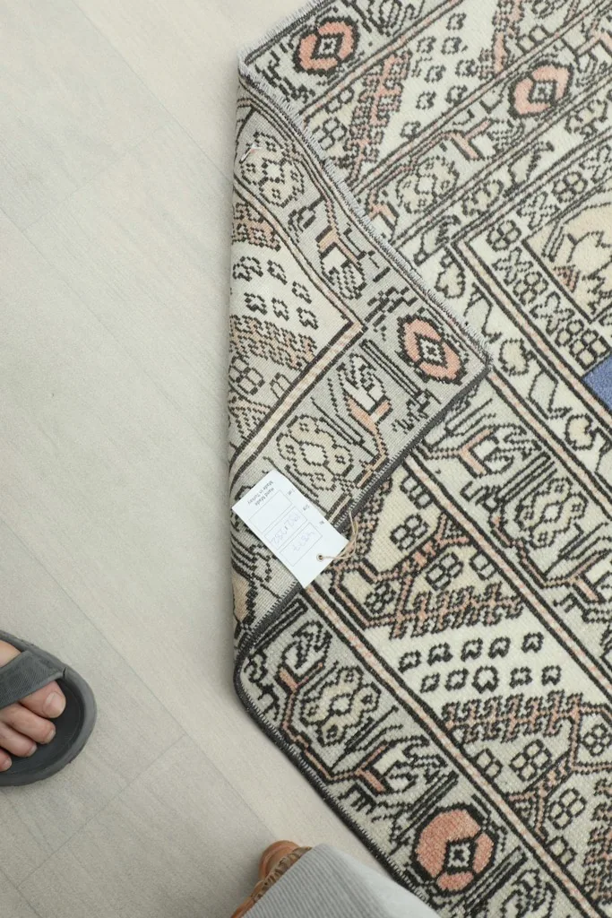 View of the rug's back and foundation with a tag, showing hand-knotted detail
