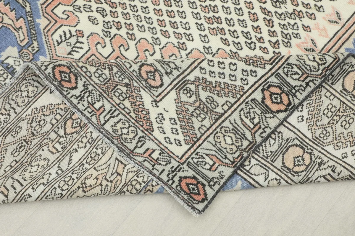 Corner of the rug folded back, revealing the reverse side of the hand-knotted construction