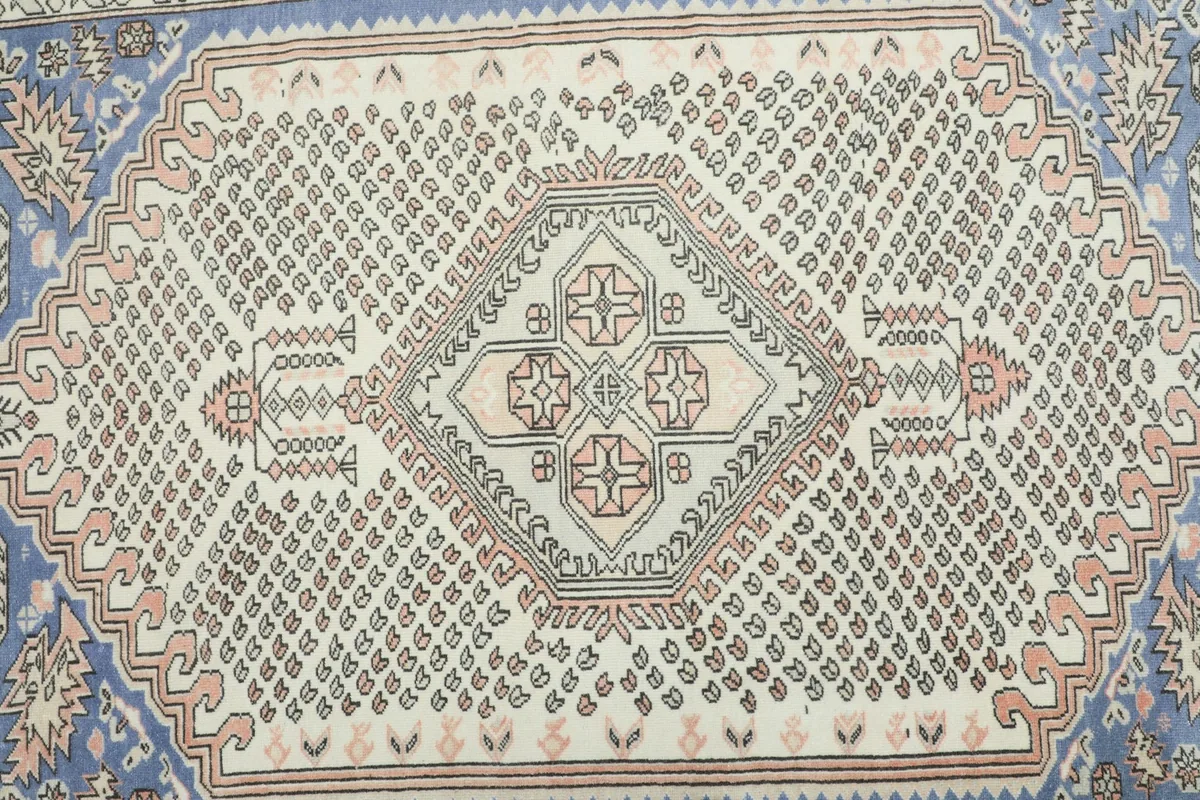 Overhead view of the rug's central ivory field with blue and rose geometric patterns