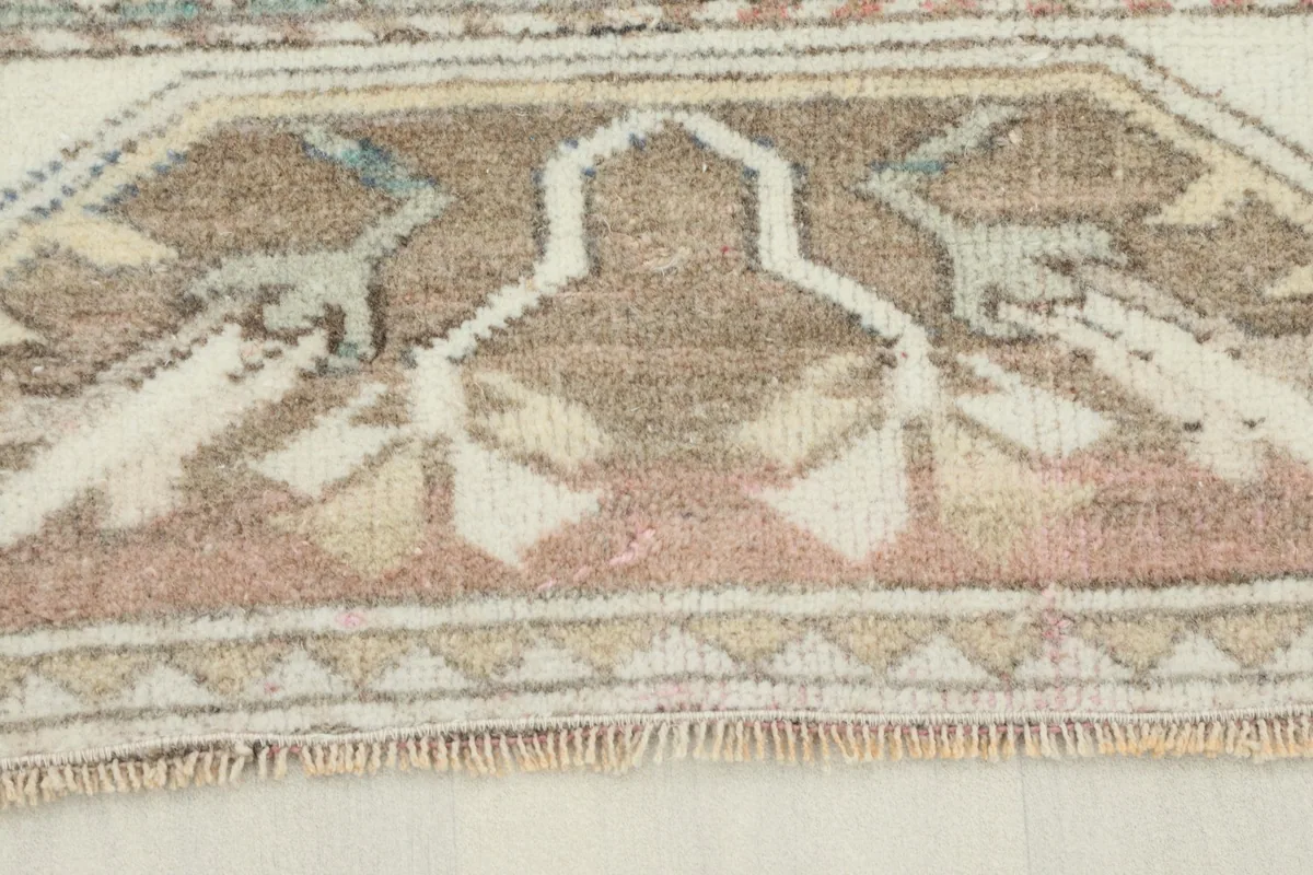 Close-up detail of the beige and brown border with geometric patterns and short fringes