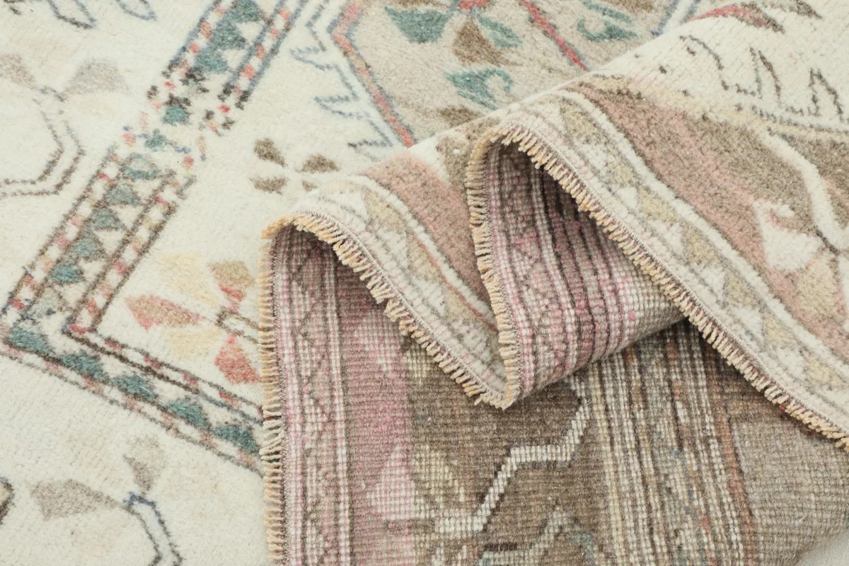 Side view of the vintage rug folded, showing the pile and intricate weave