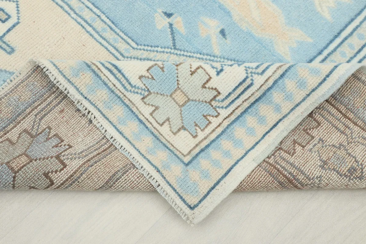 Corner of the rug folded back to reveal the hand-knotted cotton foundation and wool pile