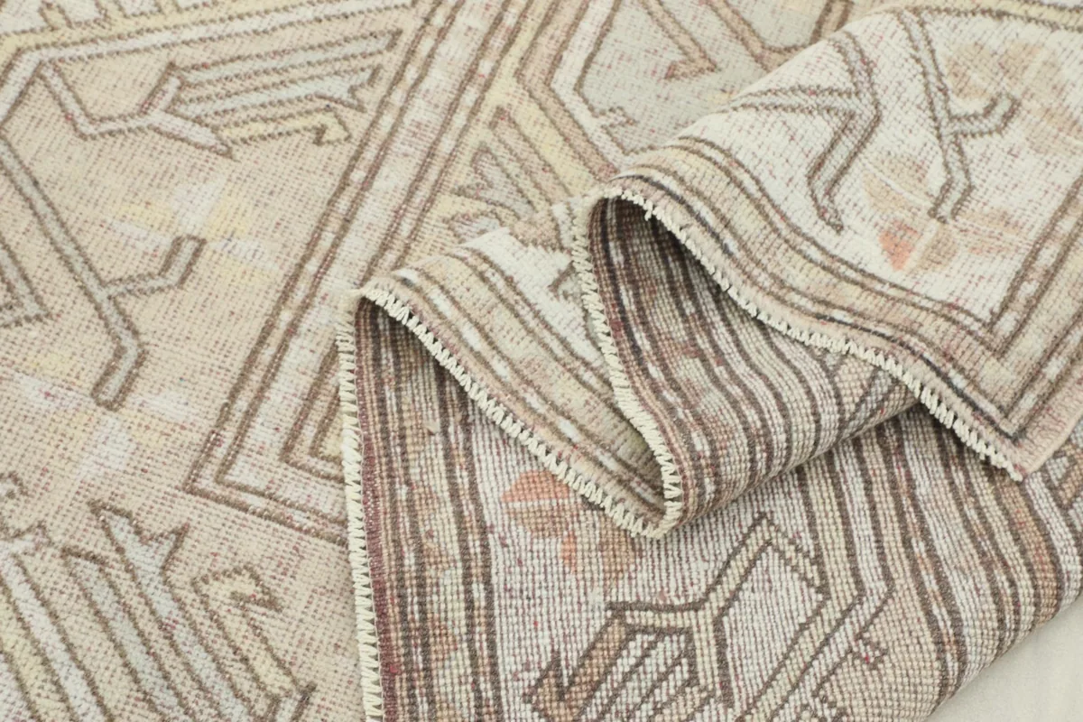 Close-up of the rug's low pile and texture, with a gentle fold showing the wool fibers.