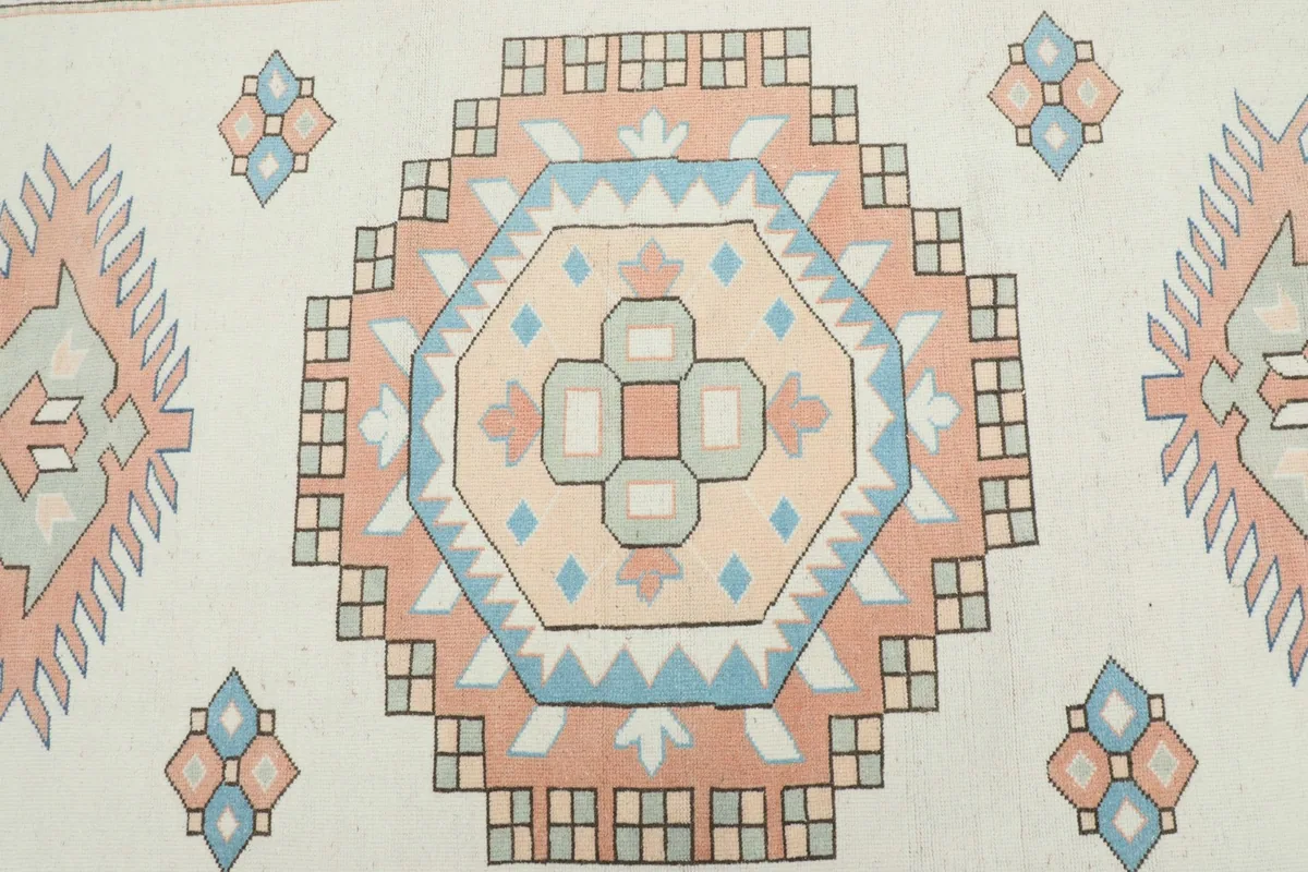 Overhead view focusing on the central geometric medallion and surrounding motifs in cream, rose, and blue.