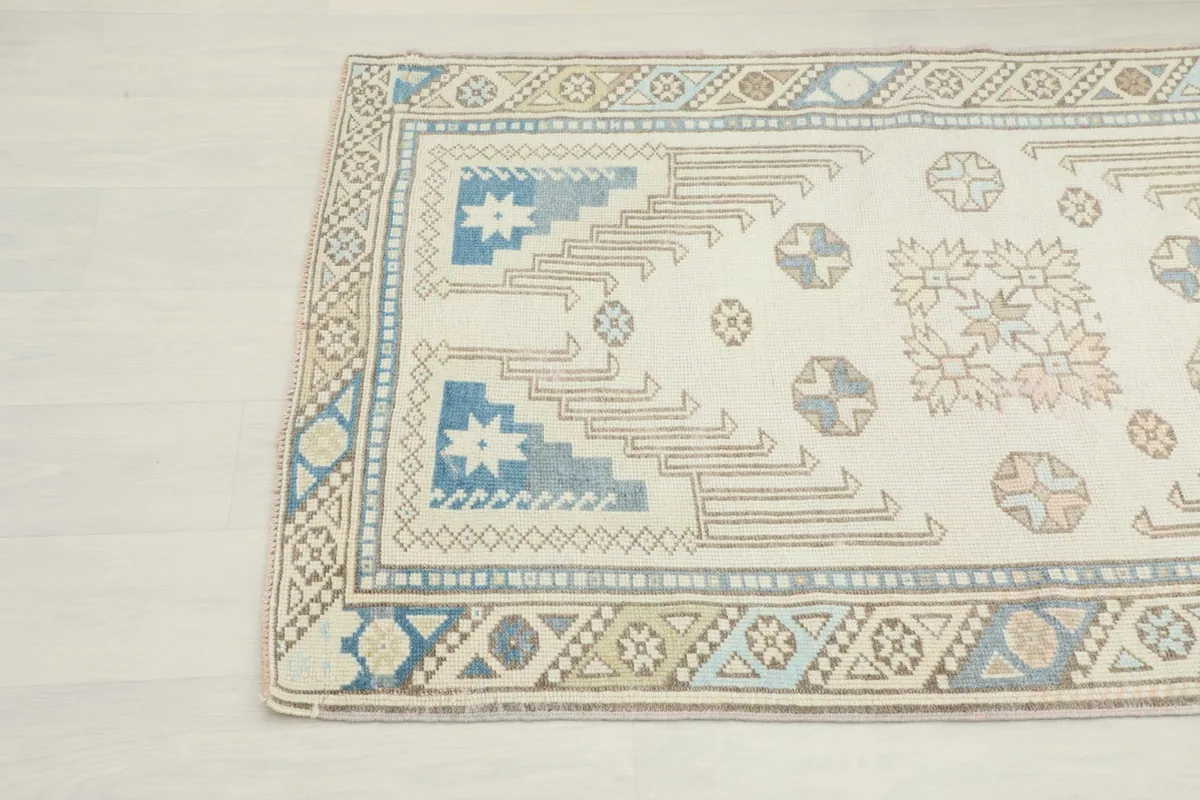 Close-up detail of the top left corner of the vintage ivory rug with geometric motifs