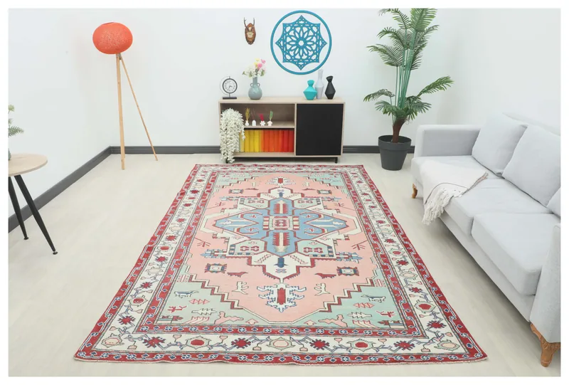 Full top view of a 6'3" x 9'8" pink, blue, and red geometric Anatolian vintage rug on a white floor.