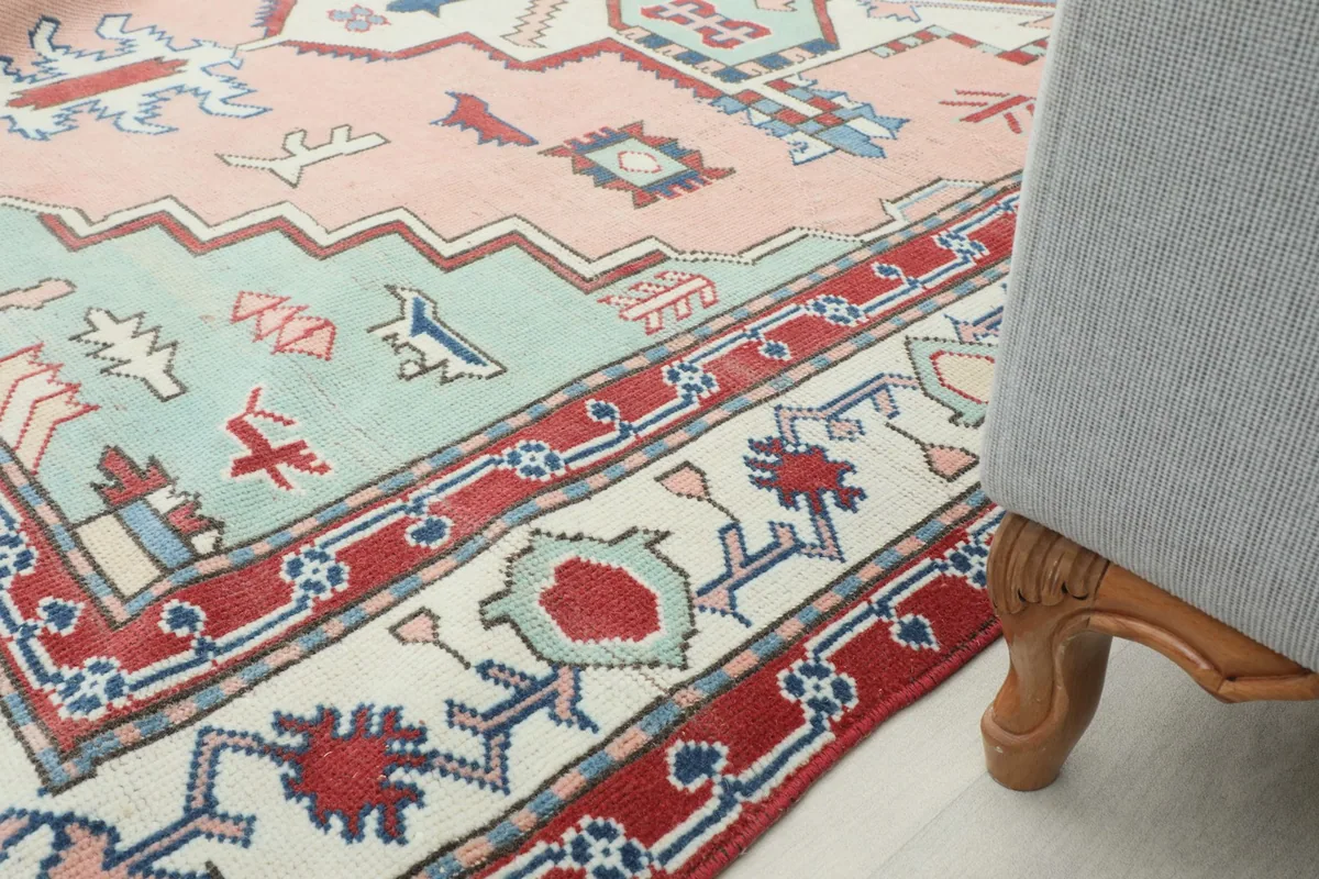 Close-up of the rug's patterns and colors, with a furniture leg at the edge, showing pile height.