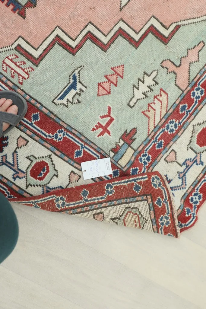 View of the rug's underside and a small label, demonstrating its hand-knotted construction.