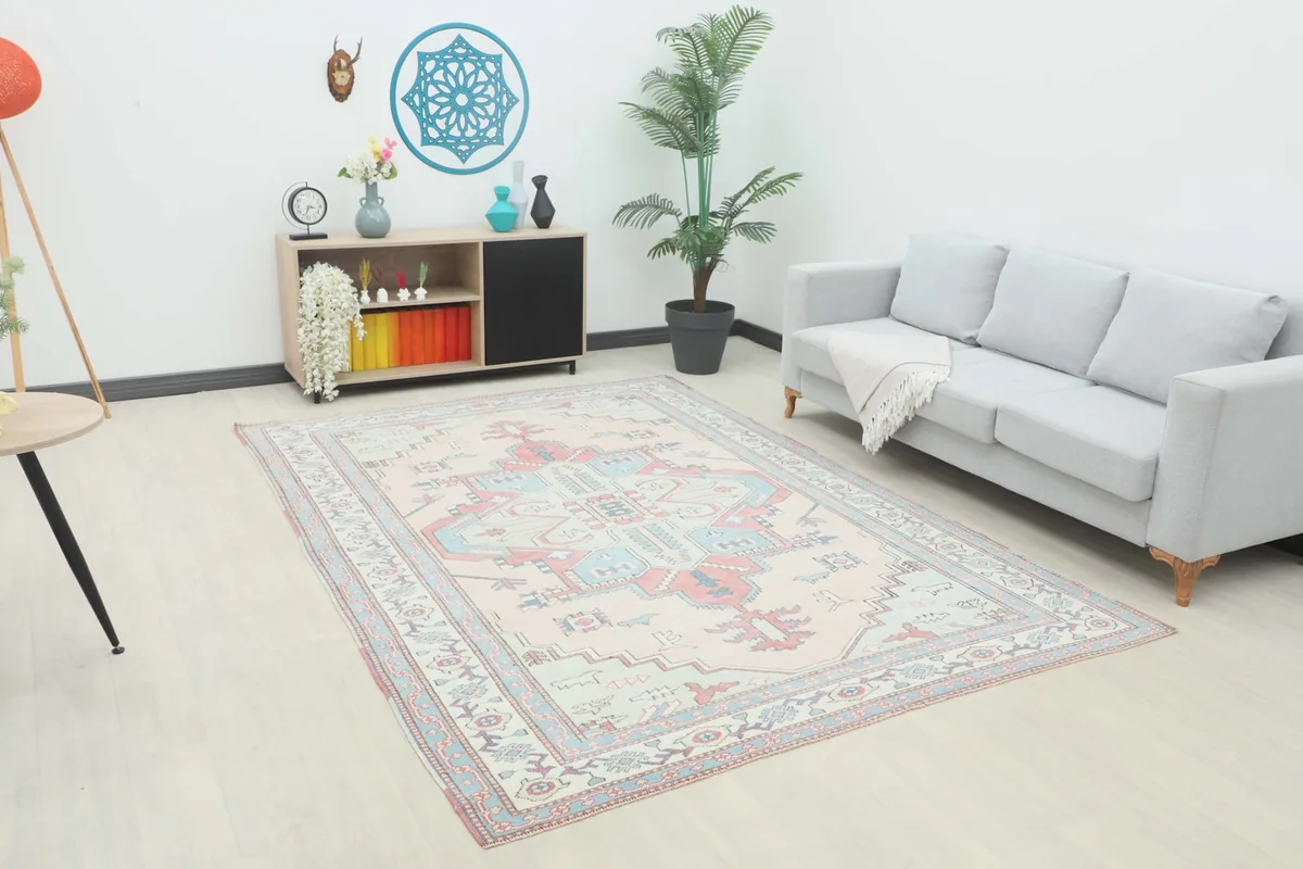 Vintage pink and blue geometric rug displayed in a living room setting with a light gray sofa.