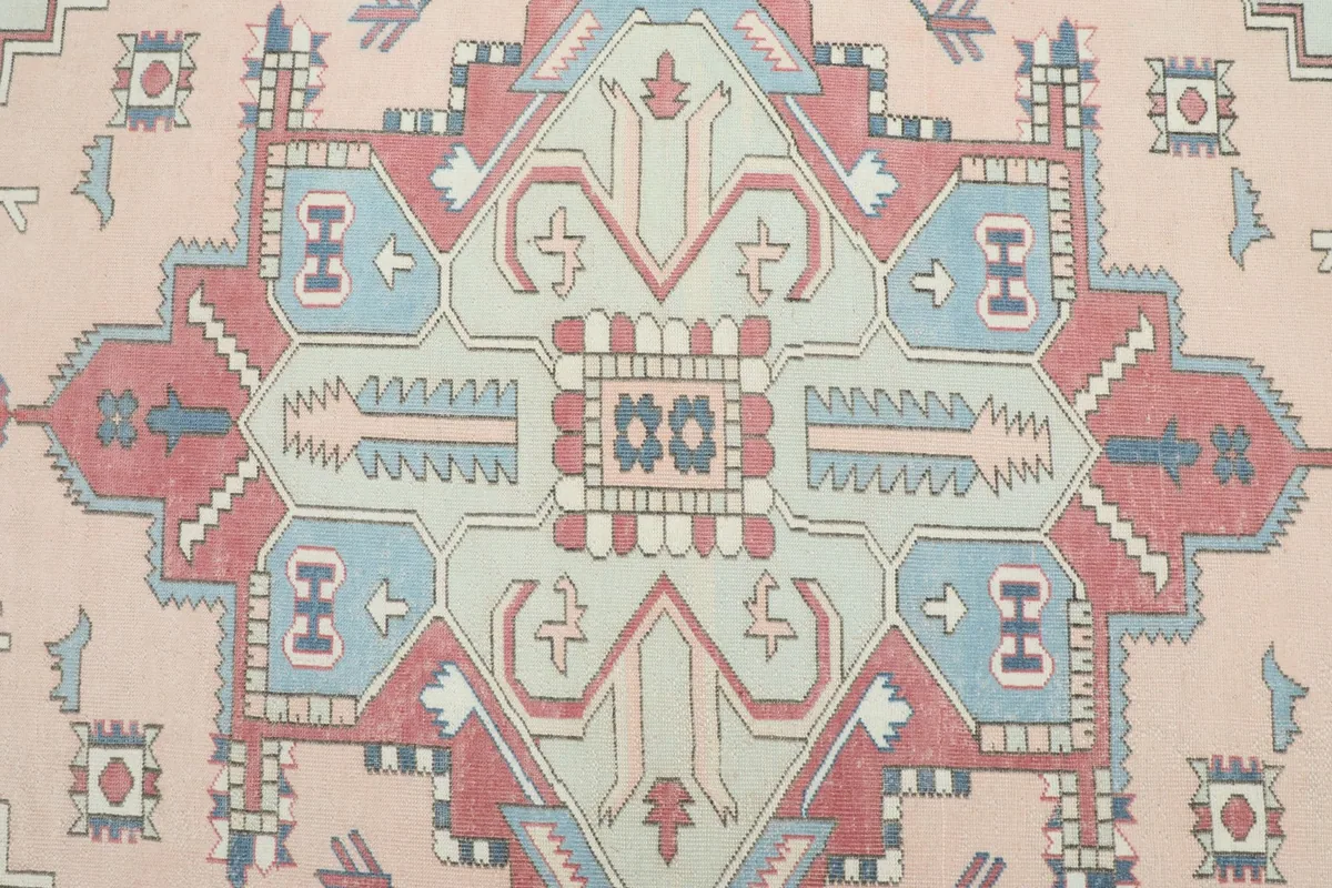 Detailed view of the central medallion and surrounding geometric motifs in pink, red, and blue.