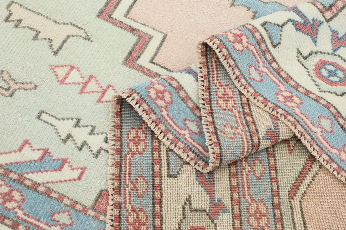 Folded section of the rug, showing the border design and the texture of the low wool pile.