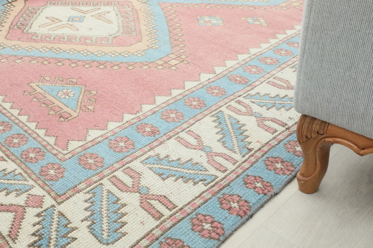 View of the rug's edge next to a furniture leg, showcasing the border design and overall color palette