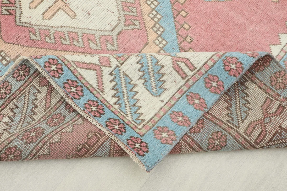 Corner of the rug folded back, revealing the reverse side with visible knotting and border patterns