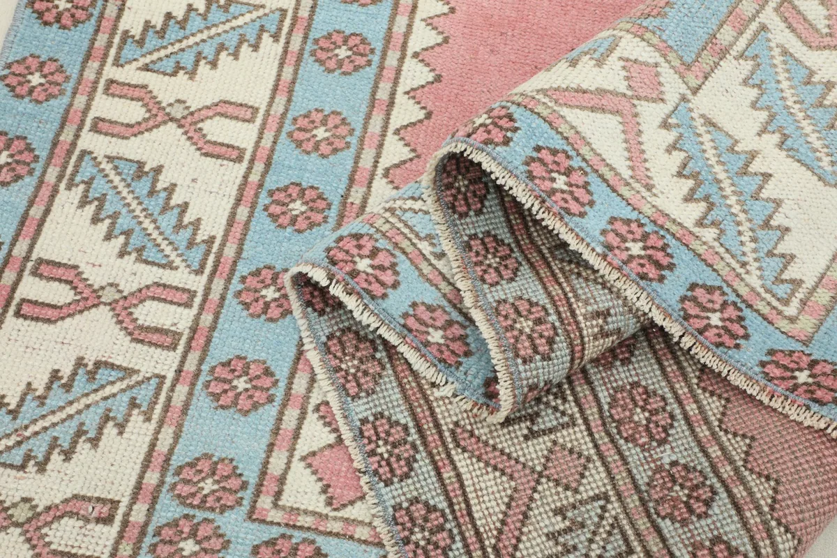 Rug folded to show the thickness of the hand-knotted wool pile and the intricate border designs