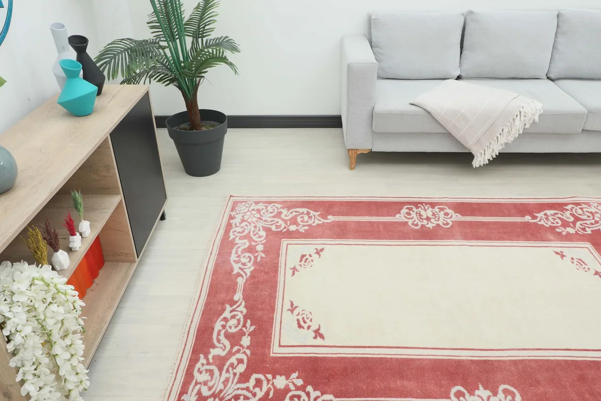 Angle view of the rose and ivory rug in a living room with a sofa and cabinet