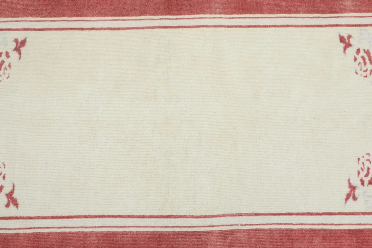 Detail view of the plain ivory central field with small corner floral motifs