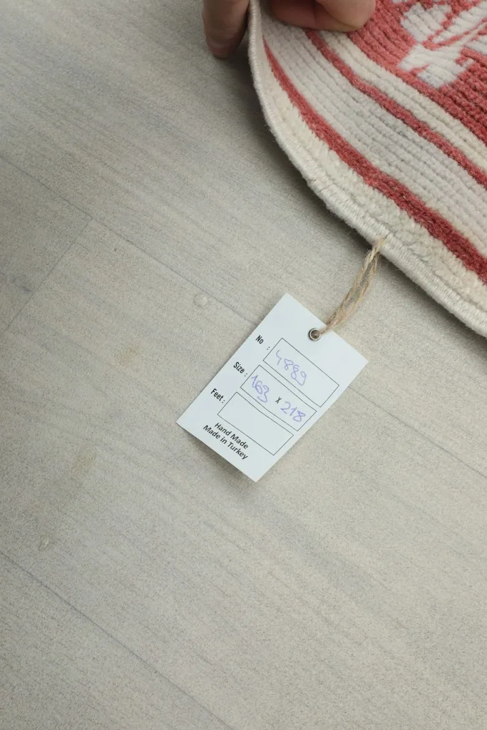 Underside view of the rug with a size tag, showing the cotton foundation