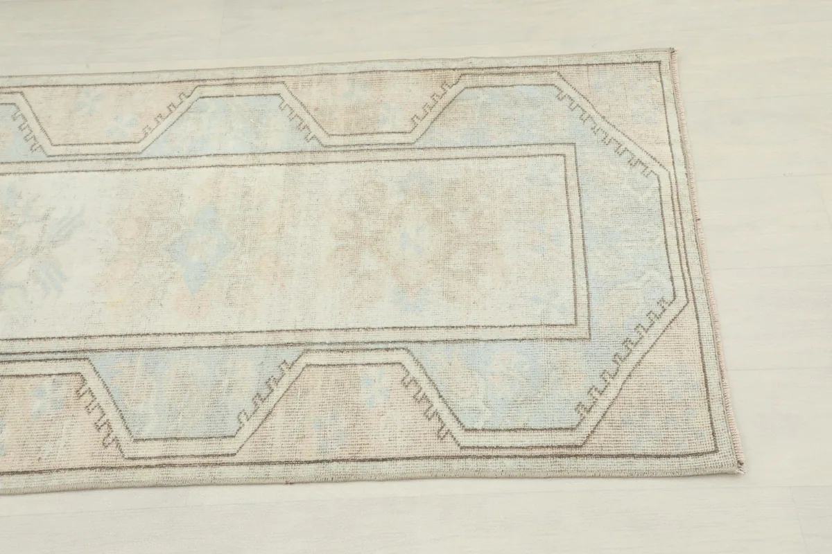 Close-up of one end of the rug, highlighting the geometric border and faint central motifs