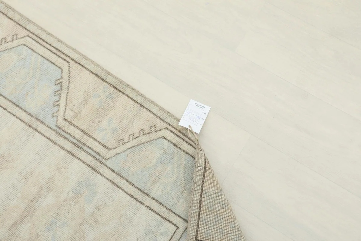 Underside of the rug near a corner, showing the hand-knotted cotton foundation and tag