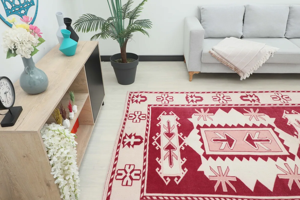 Angle view of the red and ivory vintage rug in a living space, showing its placement relative to furniture.