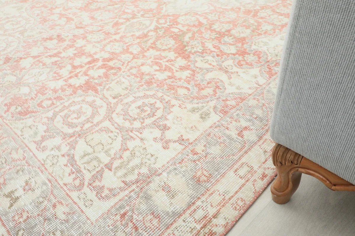 Partial view of the rug next to a chair leg, showing its integration into a living space.
