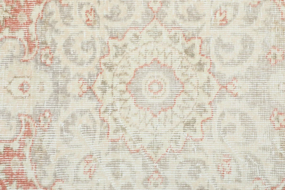 Close-up of the distressed wool pile showing the intricate floral motifs and color variations.