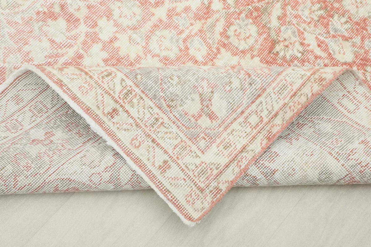 Folded corner of the rug revealing the hand-knotted cotton foundation and reverse side of the pattern.