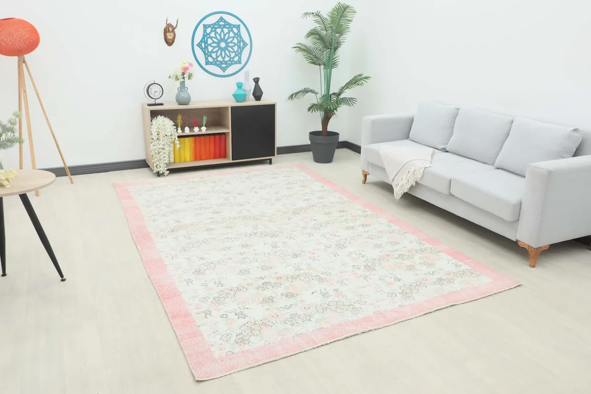 Large vintage area rug displayed in a bright living room setting with a light gray sofa