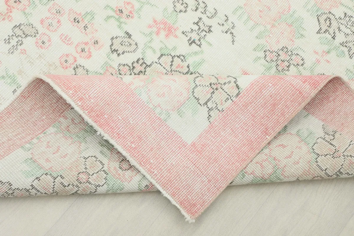 Underside of the rug revealed by a folded corner, showing the cotton foundation and knotting