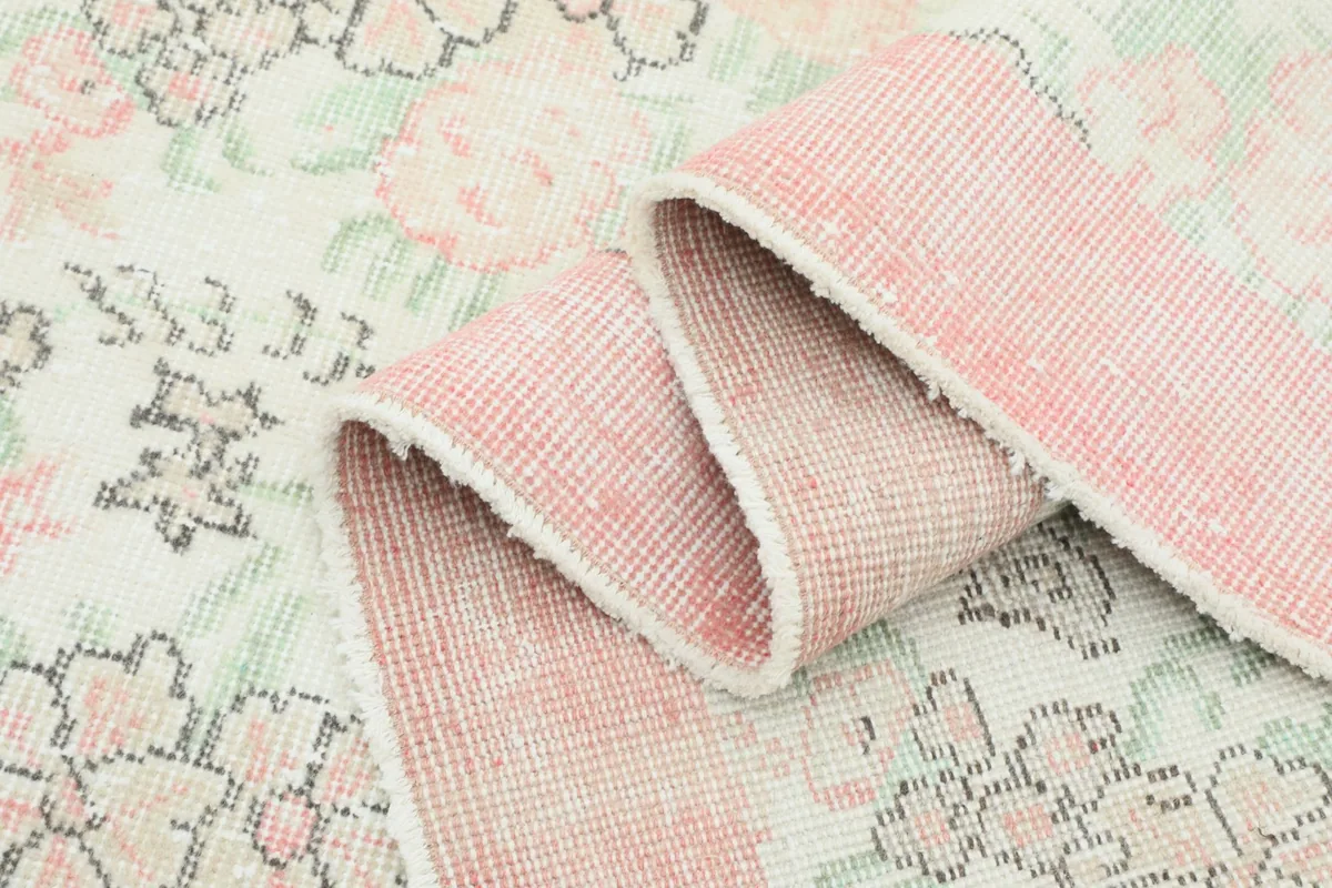 Rolled section of the rug, emphasizing the texture of the pink border and the pile