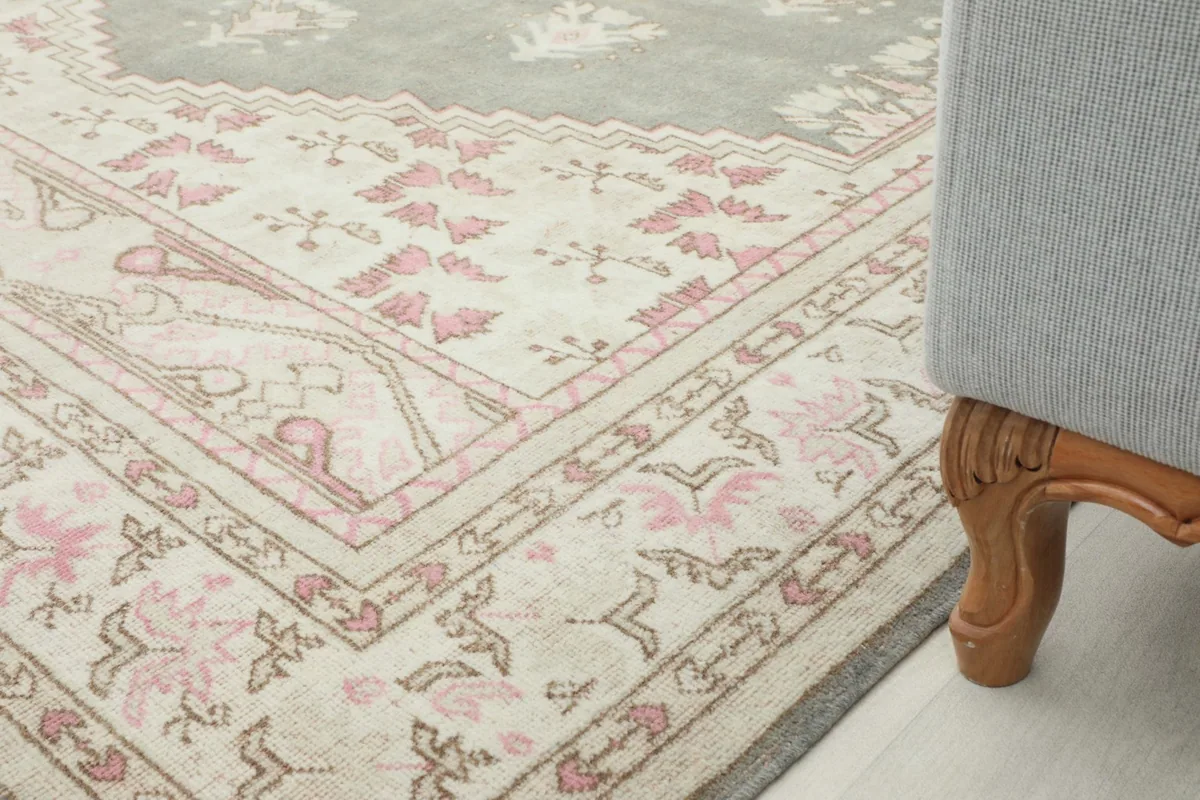 Rug corner in a room setting, next to a furniture leg, showcasing the border design.