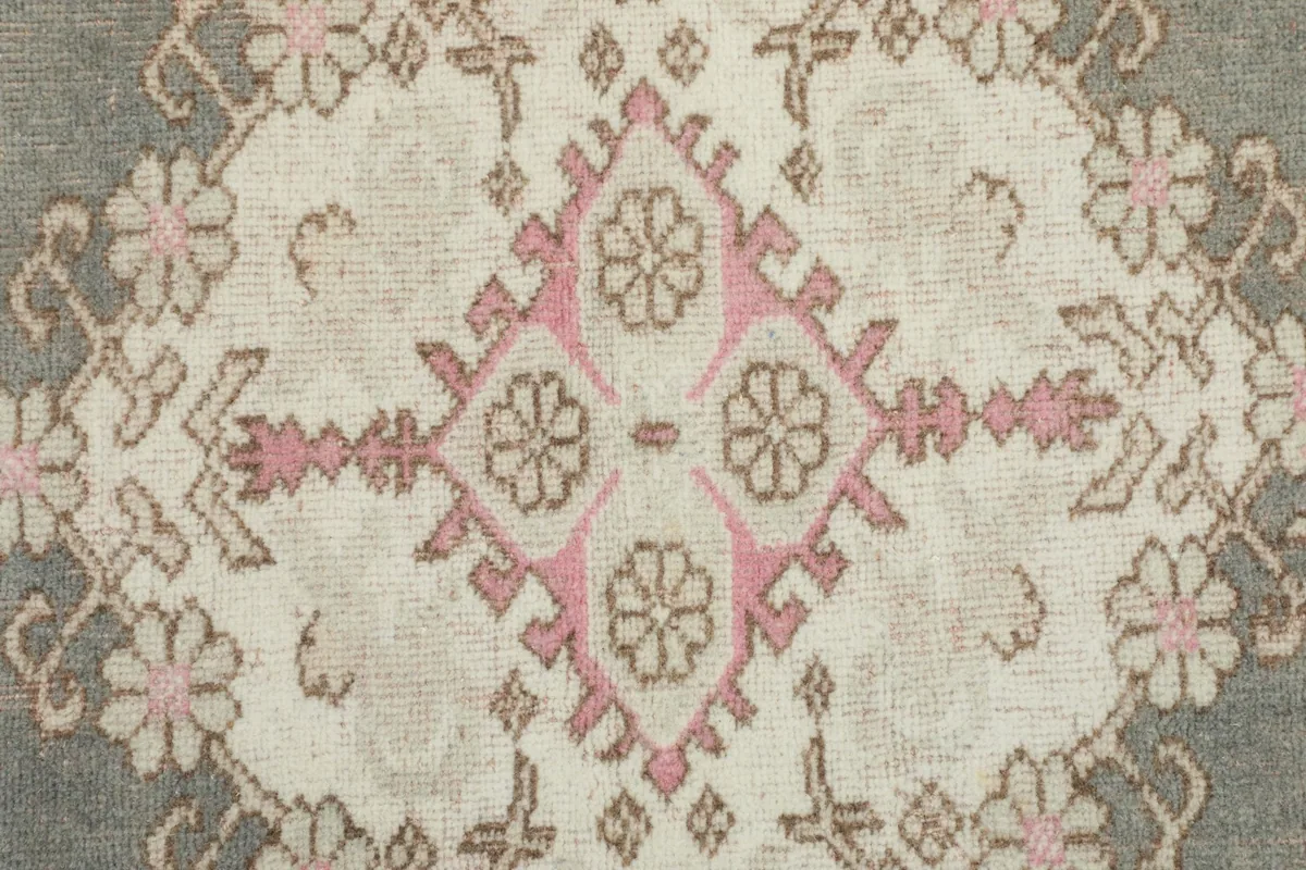 Detailed view of the central medallion design, highlighting the pink and beige patterns.