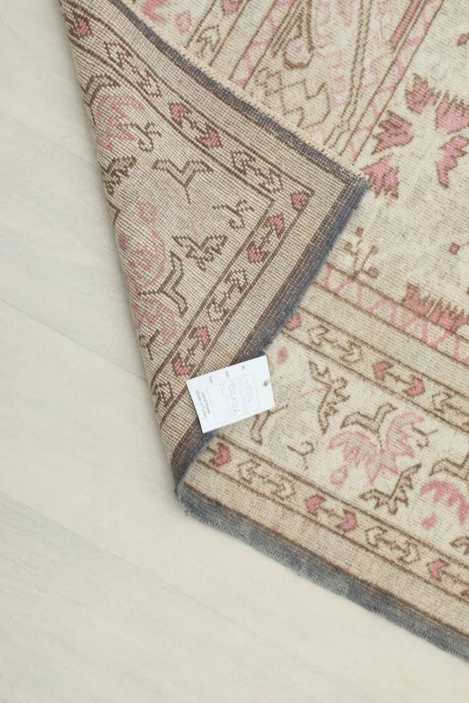 View of the rug's back and edge, displaying the hand-knotted construction and a product tag.