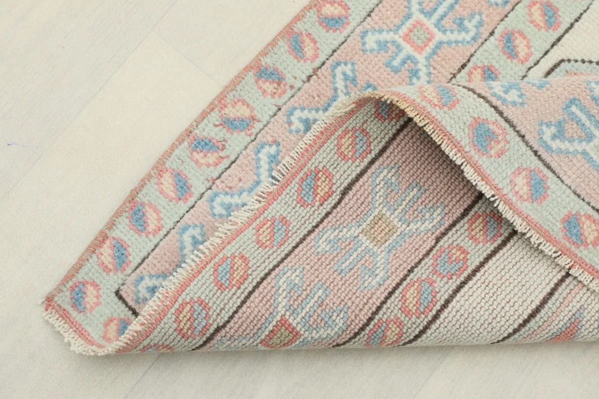 View of the rug's reverse side, showing the hand-knotted cotton foundation and wool knots.